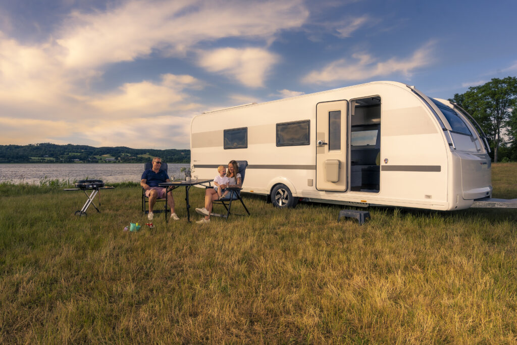 Modern husvagn på campingplats i kvällssol under campingsemester.